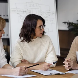 Discuție între colege în jurul unei mese
